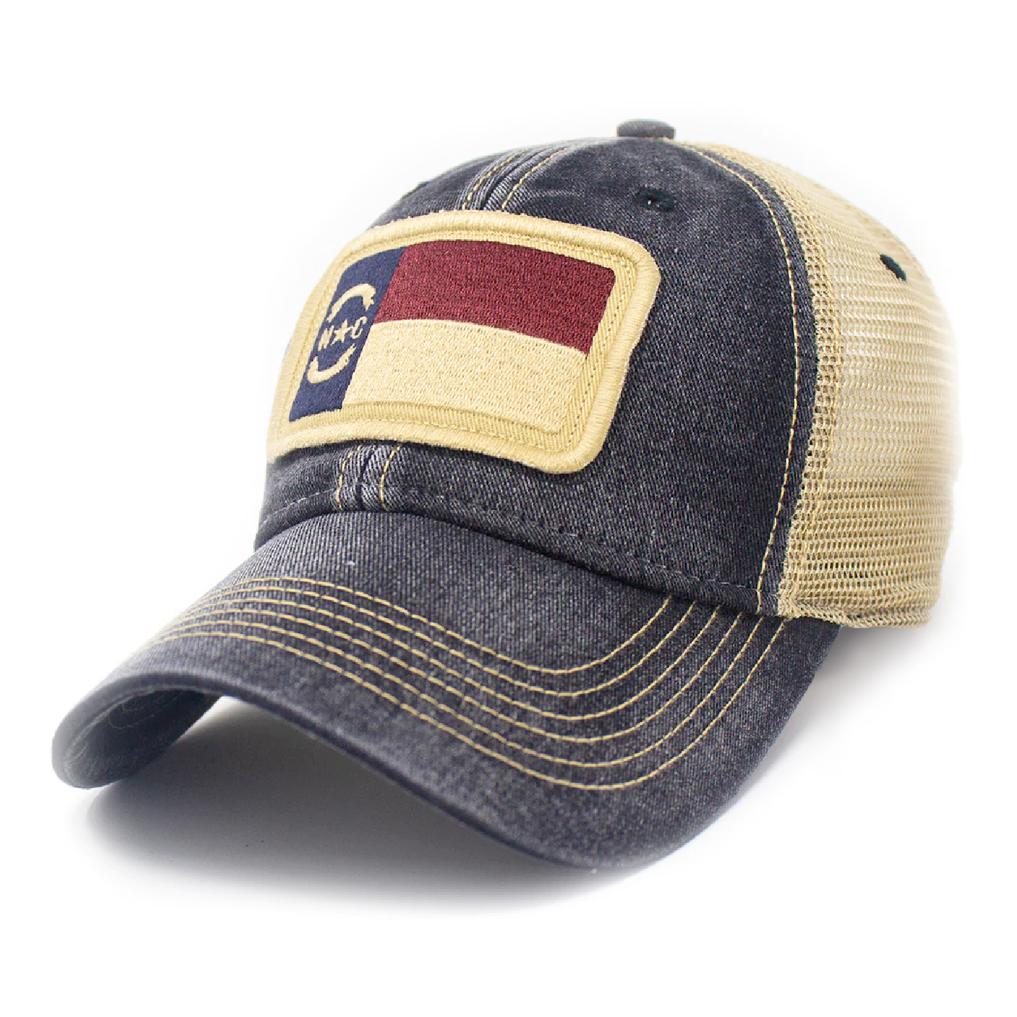 Trucker hat with khaki colored mesh backing, black cotton front panel and bill with tan stitching. Ballcap has an embroidered patch of the North Carolina flag in in the center.